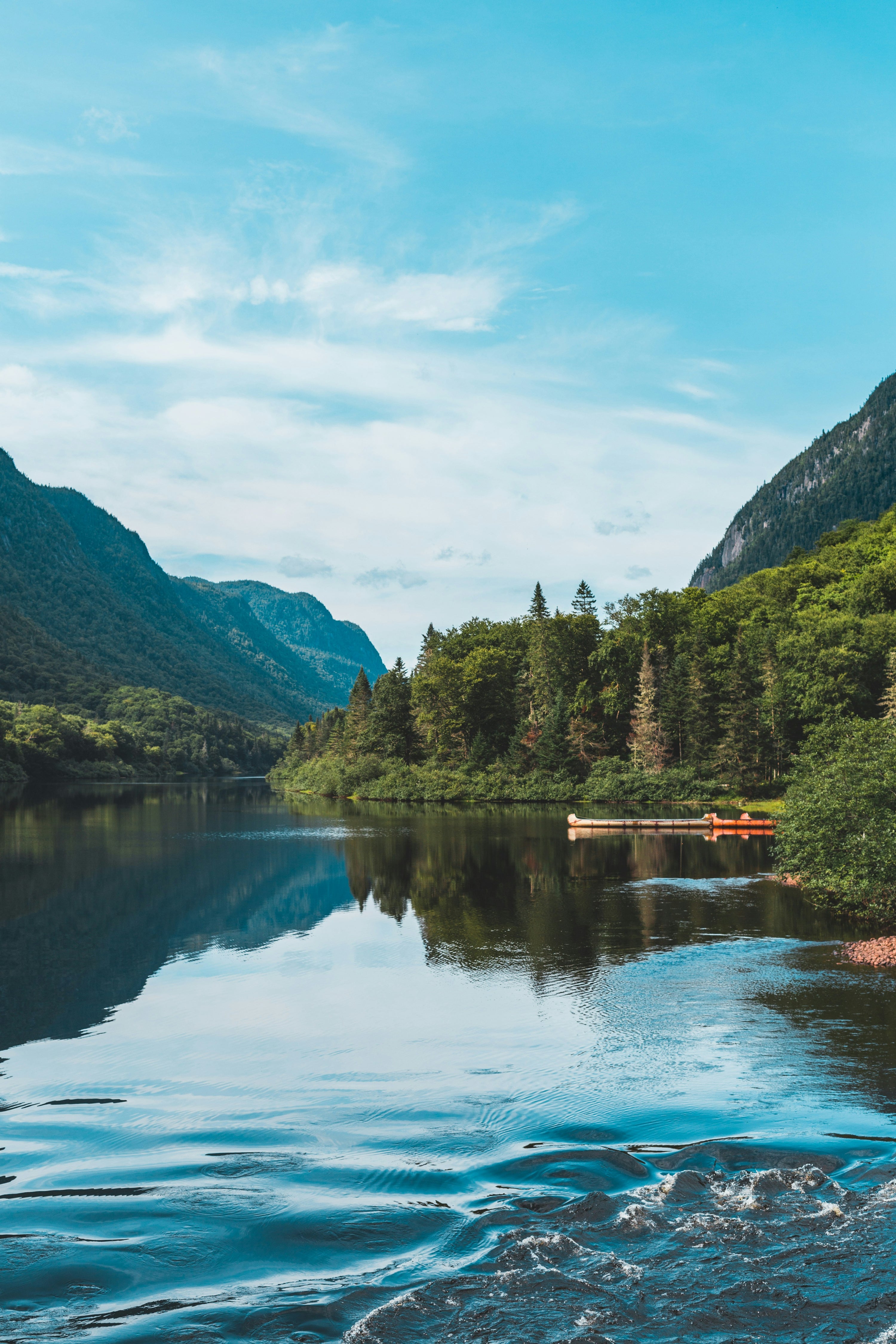Lake surrounded by green mountains and trees on a clear day